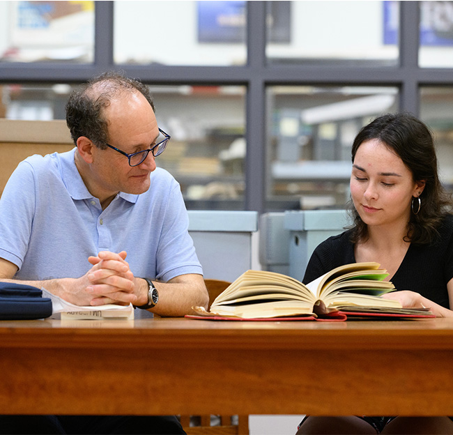 A professor assists a student with their research.