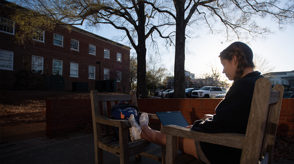 Student sitting outside beside the koi pond outside the Sally McDonnell Barksdale Honors College