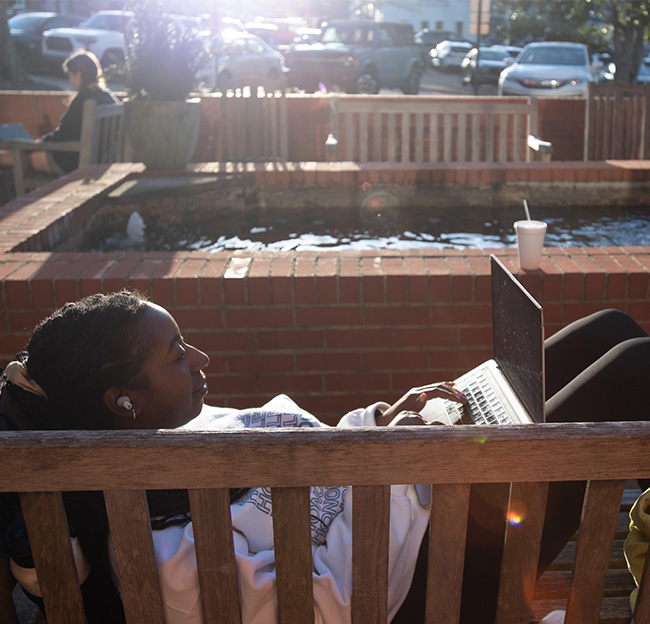 A student studies beside the koi pond outside the Sally McDonnell Barksdale Honors College