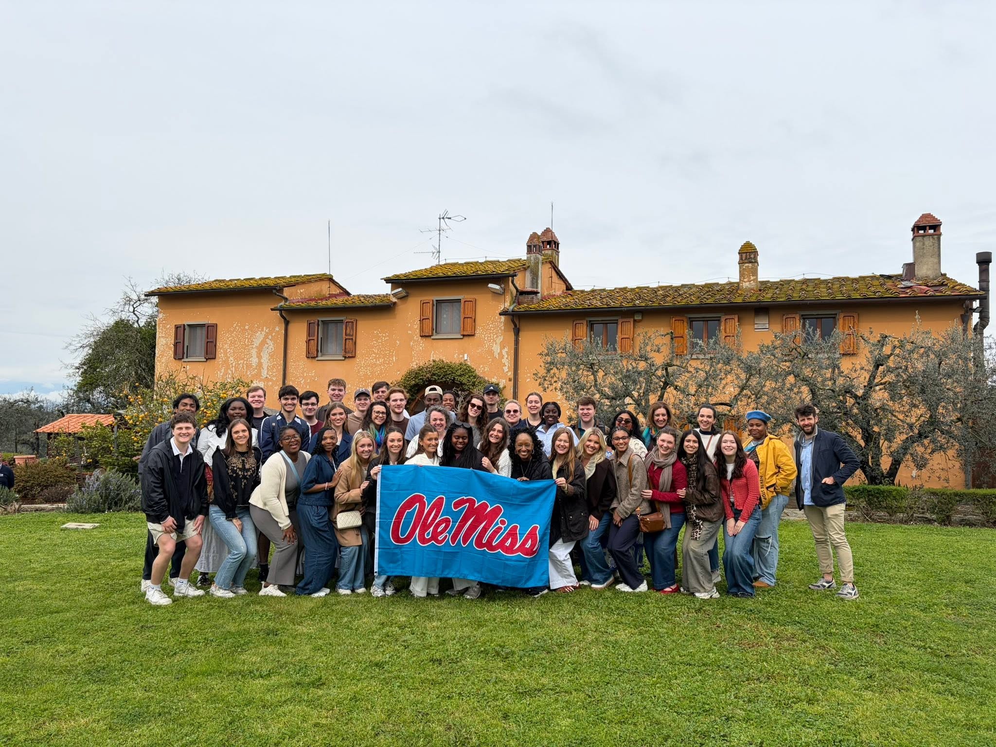 Honors Students and Faculty stand with the UM flag in Northern Italy